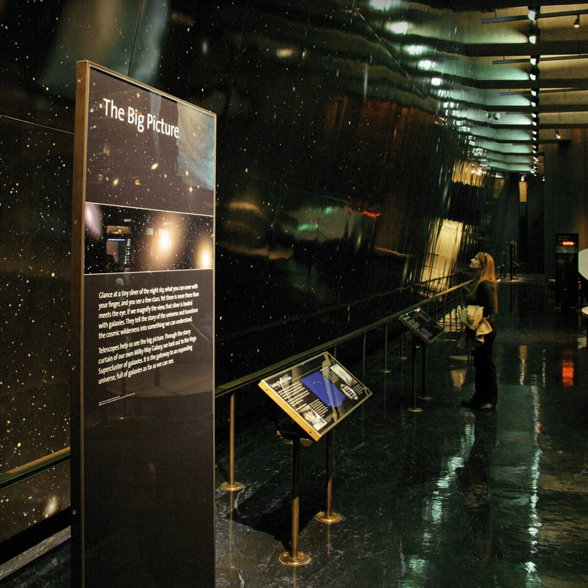 A large astronomical image stretches into the distance on a large wall. Informative exhibit panels are in the foreground.