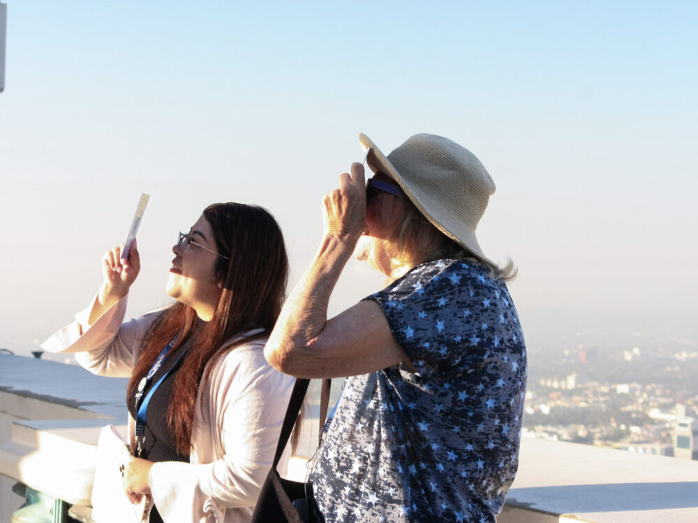 People looking at the sun through their eclipse through a protective solar shade
