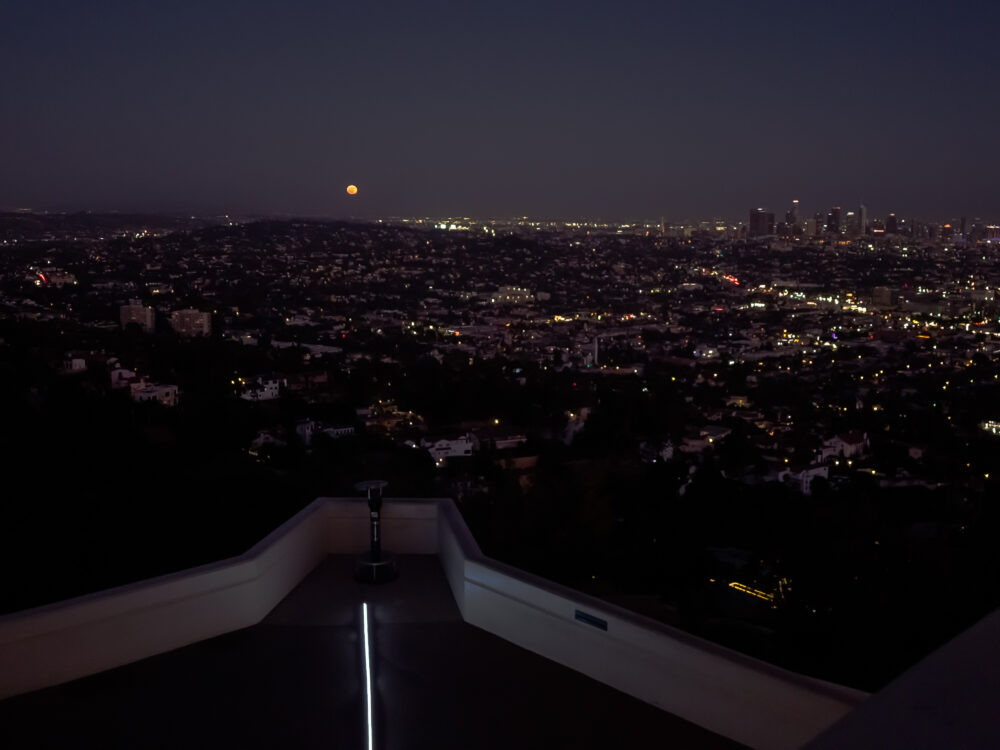 An orange moon rising on the eastern horizon