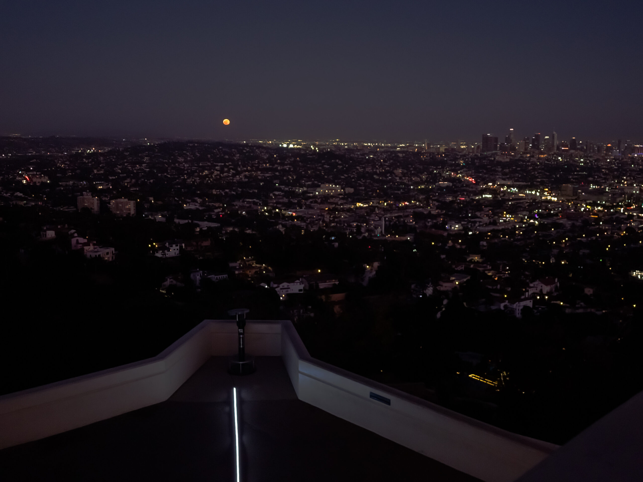 An orange moon rising on the eastern horizon