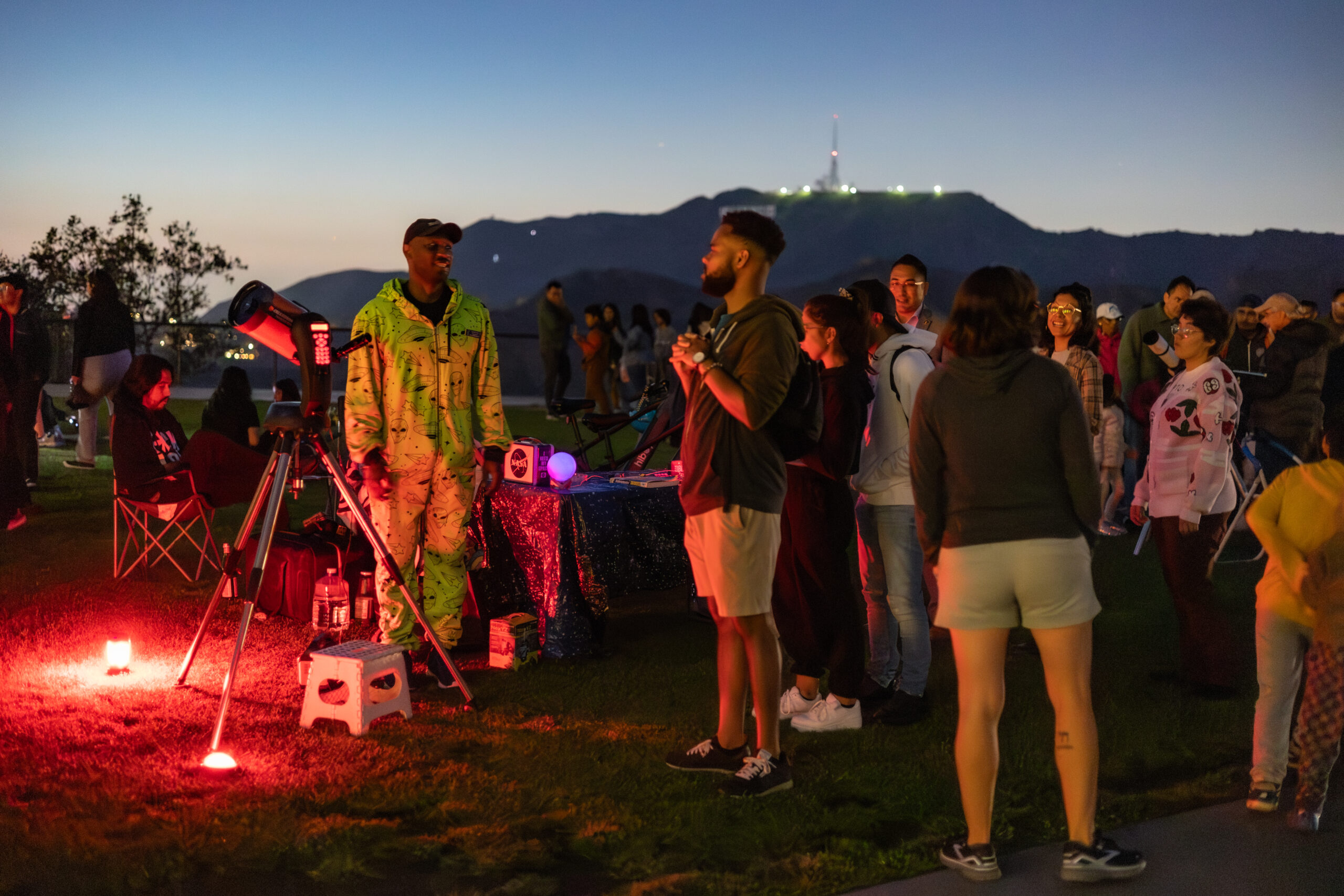 A Telescope Demonstrator greets a line of people waiting to look through the lawn telescope.