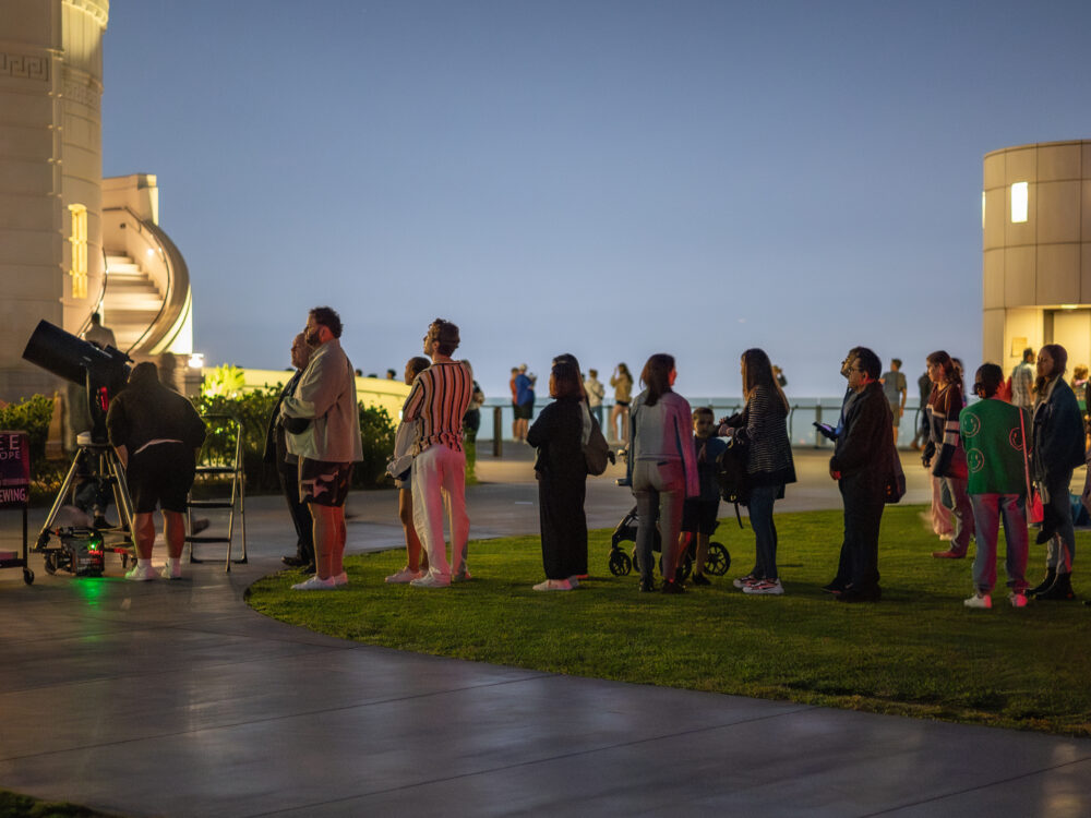 Patrons wait in line to look through a lawn telescope.