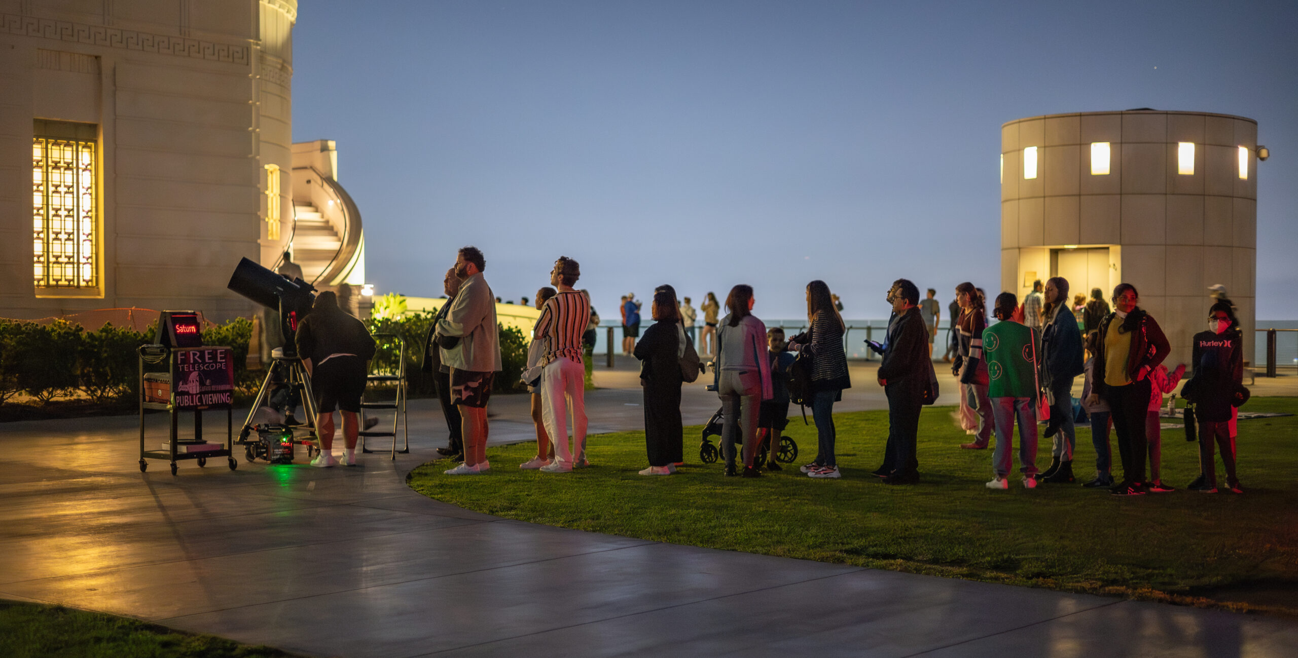 Patrons wait in line to look through a lawn telescope.
