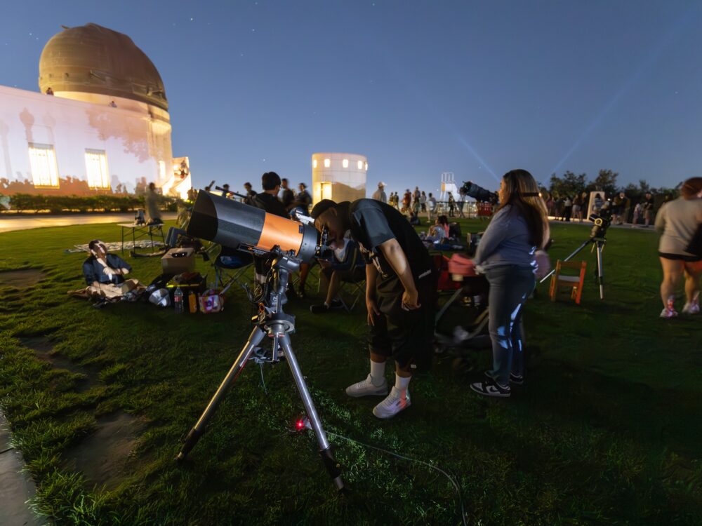 A man looks through a lawn telescope.
