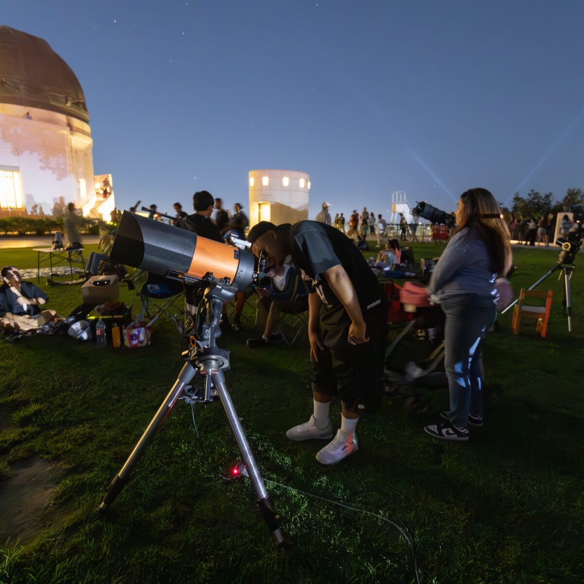 A man looks through a lawn telescope.