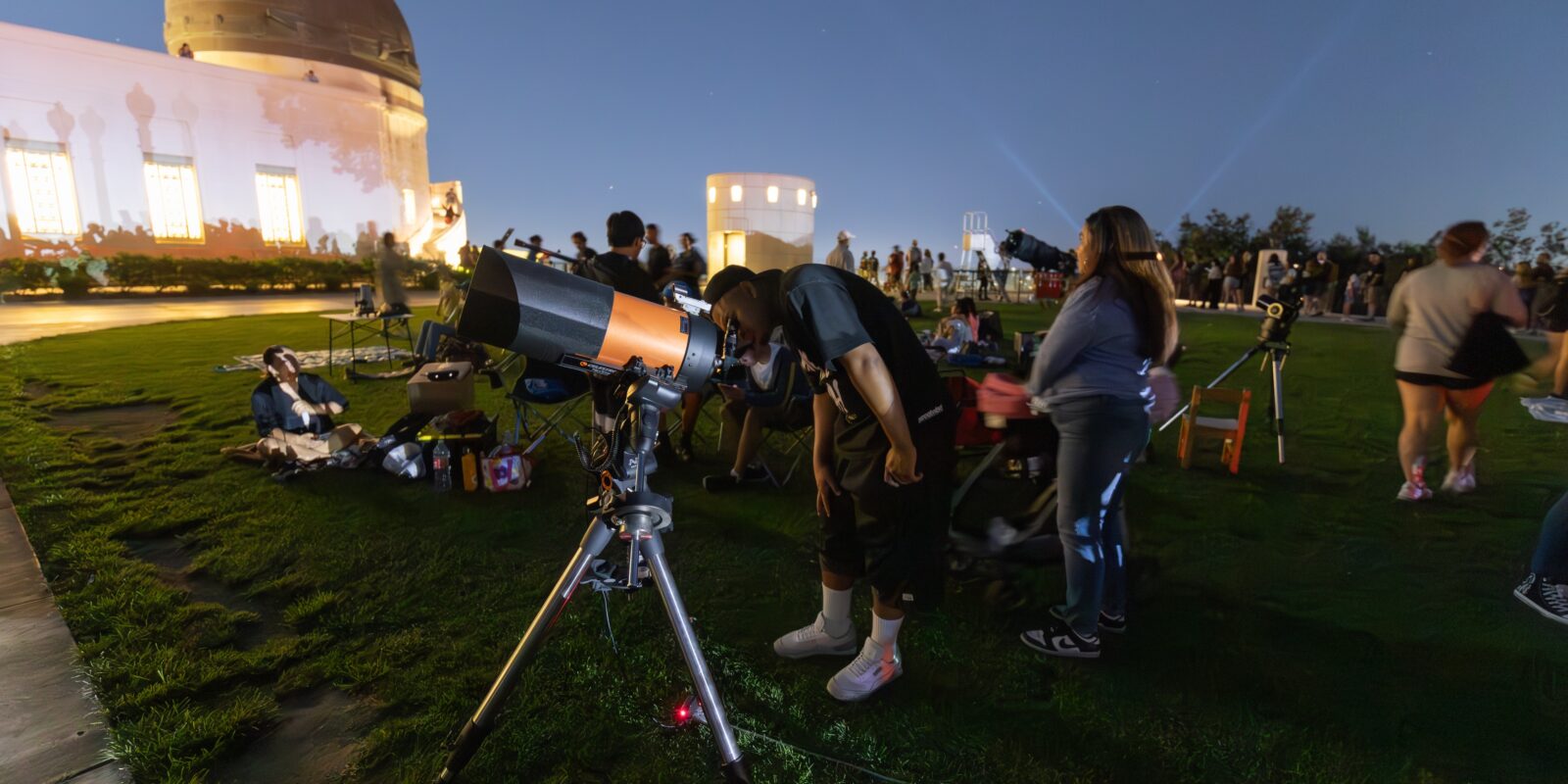 A man looks through a lawn telescope.