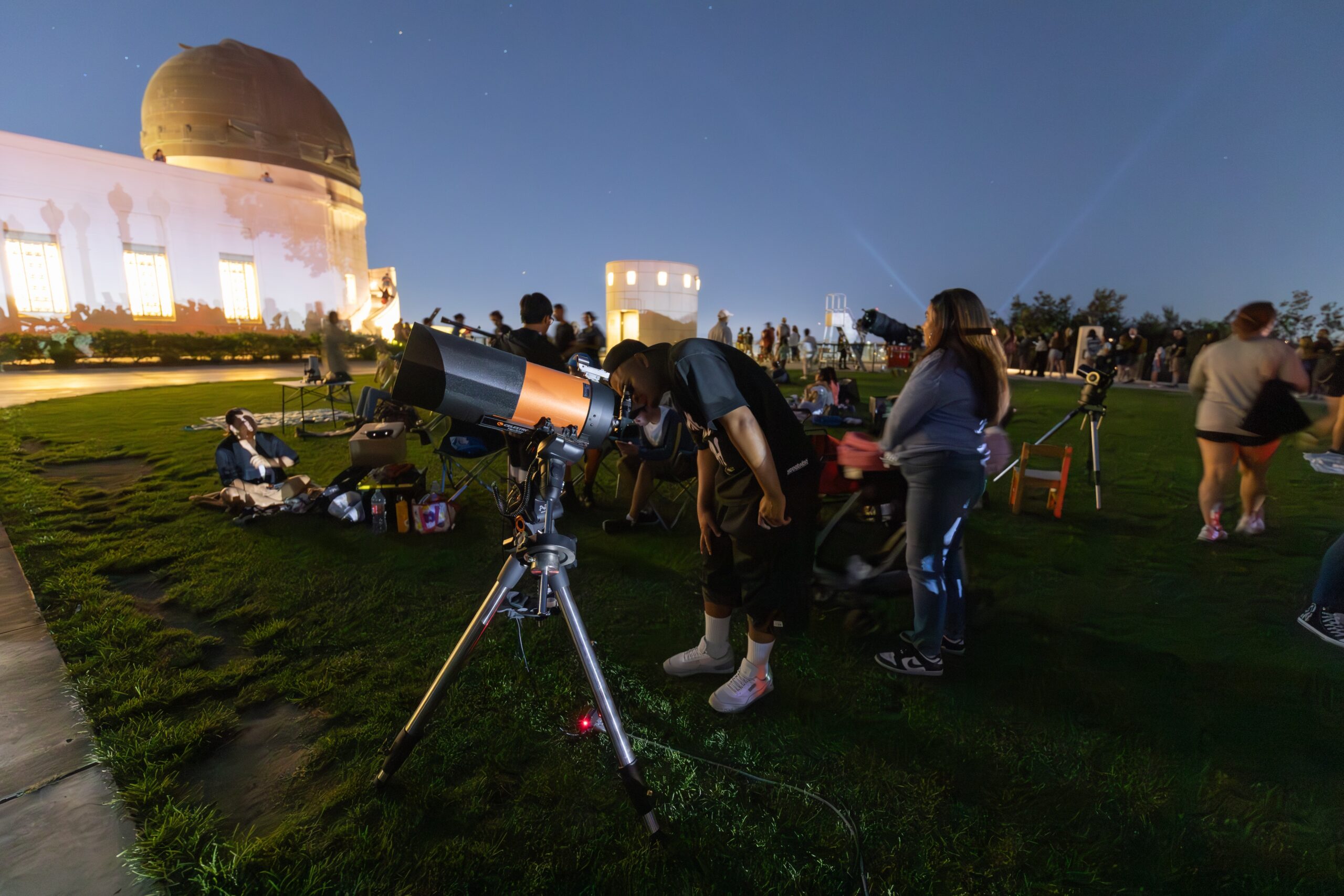 A man looks through a lawn telescope.