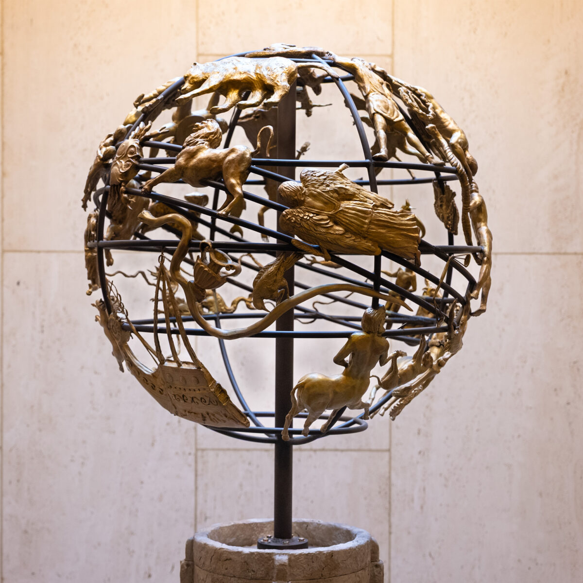A wire globe covered with bronze zodiac figures.