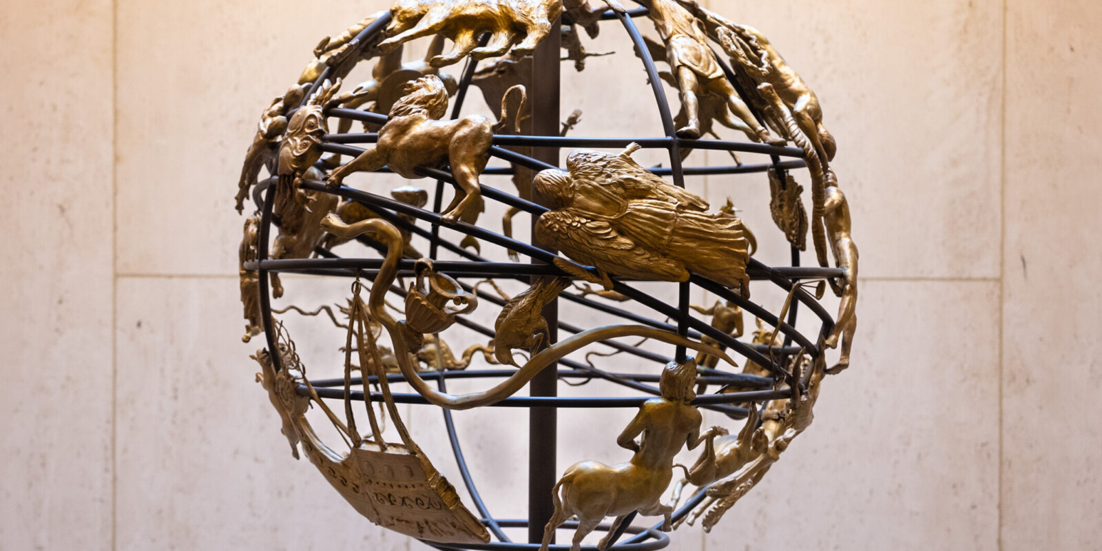 A wire globe covered with bronze zodiac figures.